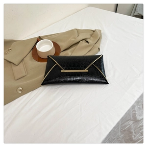 Detail of black crocodile texture envelope clutch with elegant gold metal trim and clasp