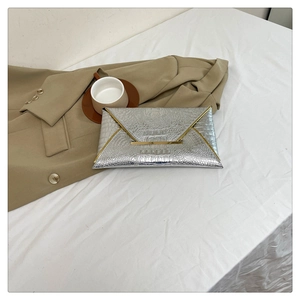 Detail view of silver crocodile embossed envelope clutch with metallic gold trim and flap