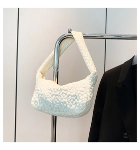 Détail de la texture florale matelassée et de la bandoulière de ce sac à main blanc