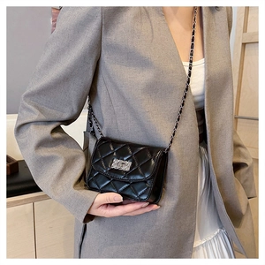 Crossbody view of black quilted square bag with silver chain and glossy finish