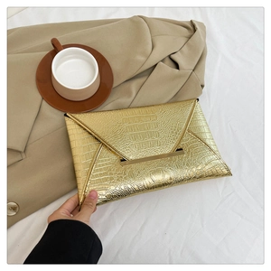 Detailed close-up of golden crocodile pattern envelope clutch bag with metal buckle