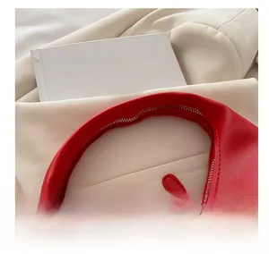 Detailed close-up of a stylish red leather crescent bag with silver dual zippers