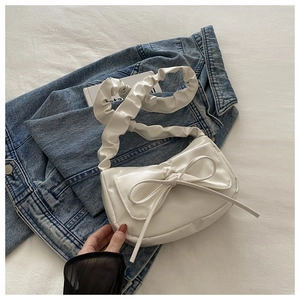 Detail of white PU leather shoulder bag featuring a large bow and cloud pleated strap
