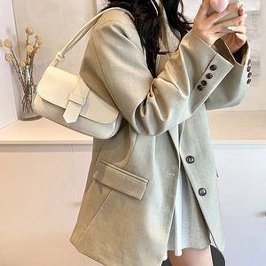 Minimalist white leather underarm bag shown in a stylish lifestyle setting with a blazer
