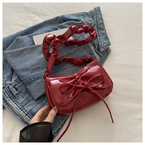 Detail of red shoulder bag with large bow and ruched cloud strap on denim fabric