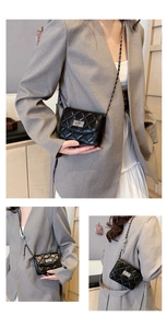 Close-up of black quilted mini bag with silver chain strap and metal lock detail