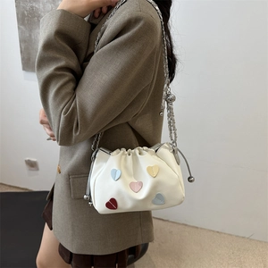 White faux leather crossbody bucket bag with colorful heart patches and silver chain