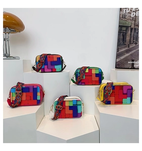 Five rainbow patchwork square bags with colorful ethnic woven shoulder straps on steps