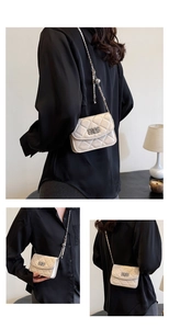 Detail of cream quilted crossbody bag featuring silver chain and adjustable pearl metal ball