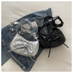 Close-up of bow-shaped ruched shoulder bags in metallic silver and glossy black PU