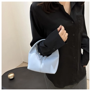 Detail of light blue crescent mini handbag featuring vertical stitching and dual zippers