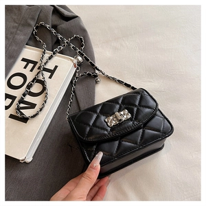 Detailed macro view of quilted black leather texture and elegant silver chain on small square bag