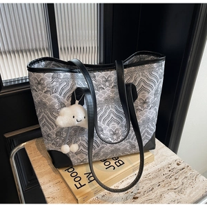 Close-up of wave pattern tote bag with white cloud plush pendant on art books