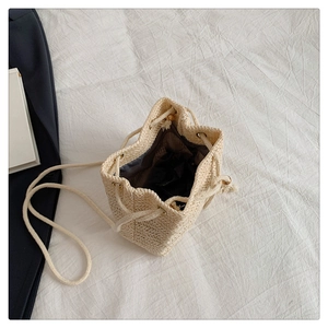 Detail of woven straw bucket bag showing drawstring closure and inner lining