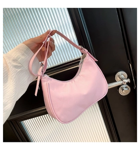 Detail of pink hobo shoulder bag held by hand, featuring smooth fabric and silver zipper