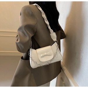 Detail of cream white leather shoulder bag with bow decor and silver floral chain strap