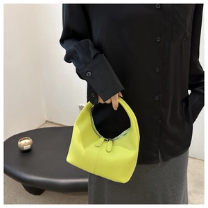 Detail of neon yellow minimalist handbag featuring dual zippers and sleek leather texture