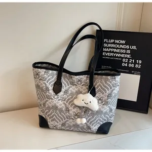 Detail of checkered tote bag featuring black leather trim and white plush cloud charm