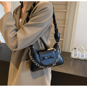 Detail view of black matte leather shoulder bag with bow and floral chain