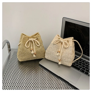 Close-up of woven straw bucket bag with drawstring closure and decorative wooden beads