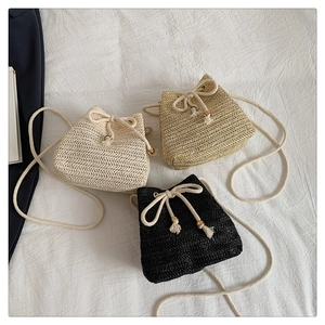 Detailed view of woven straw bucket bags with cotton drawstring and wooden bead accents
