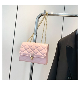 Detail of pink quilted crossbody bag with golden chain strap and metallic lock closure