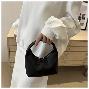 Detail of a minimalist black semi-circle handbag with matte finish and silver zippers