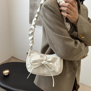 White pleated cloud shoulder bag with a bow detail on a stylish model in beige blazer