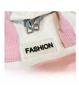 Dettaglio delle doppie cerniere argentate e targhetta Fashion sulla borsa in tela