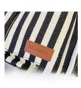 Detail of striped canvas tote showing woven texture and brown leather FASHION label