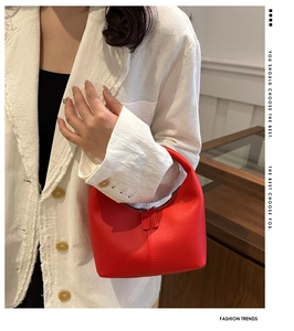 Close-up of a vibrant red crescent hobo bag held by a model in a white textured blazer