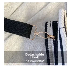 Detail of the golden detachable hook connecting black strap to striped canvas tote bag