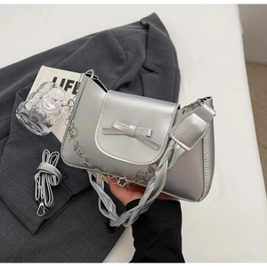Detail of silver metallic handbag with bow accent and chain handle for summer styling