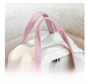 Dettaglio dei manici in tessuto rosa e etichetta fashion su zaino in nylon bianco