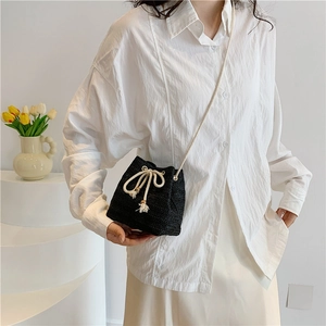 Minimalist black straw woven bucket bag with beige drawstring and chain strap
