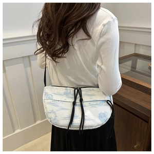 Detail of waterproof nylon tie-dye crossbody bag featuring blue toile scenery pattern