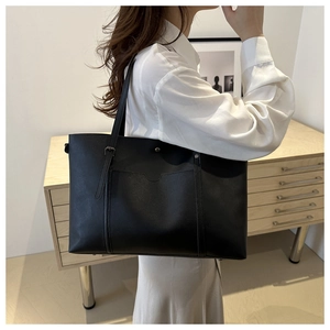 Detail view of large black tote bag with decorative stitching and fine shoulder strap