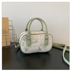 Detail of Boston bag with butterfly print, green handles and silver metal hardware