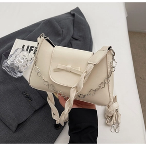 Detail of cream white PU handbag featuring leather bow and floral silver chain strap