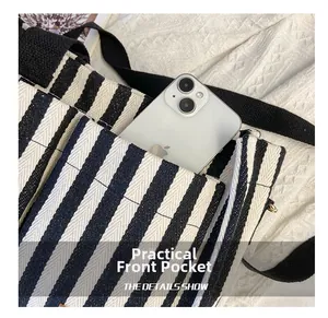 Detailed close-up of a striped canvas tote bag showing the practical front pocket and phone