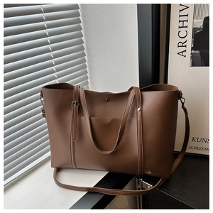 Detail of a brown leather tote bag showing textured surface and side pocket in soft light