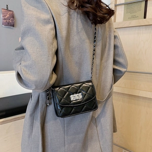 Quilted black crossbody bag with silver chain strap worn by a model in a minimalist setting