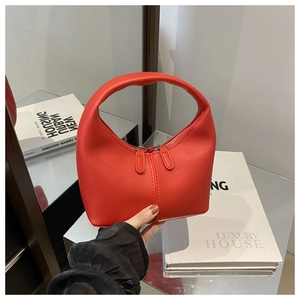 Macro view of a red leather crescent handbag with stitching details and zipper closure