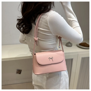 Close-up of pink crossbody bag featuring a silver metal bow and stylish knotted shoulder strap