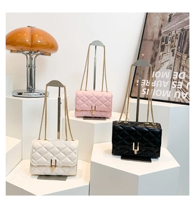 Three quilted chain bags in white, pink, and black displayed on geometric stands