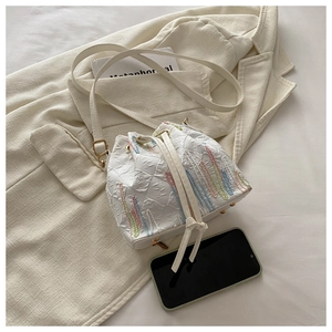 Detail of white nylon bucket bag featuring colorful embroidery and drawstring closure