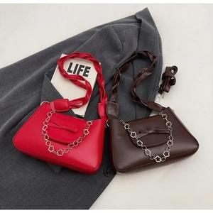 Close-up of stylish handbag with a bow detail and silver floral chain decoration