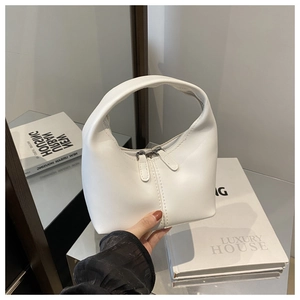 Detailed view of white half-moon handbag with vertical stitching and dual metal zippers
