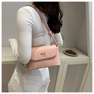 Close-up of light pink leather shoulder bag with silver bow accent and knotted strap