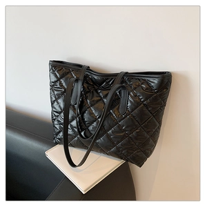 Détail du grand sac cabas matelassé noir posé sur un canapé dans un décor minimaliste